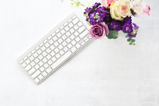 Flat lay with computer keyboard and colorful flowers