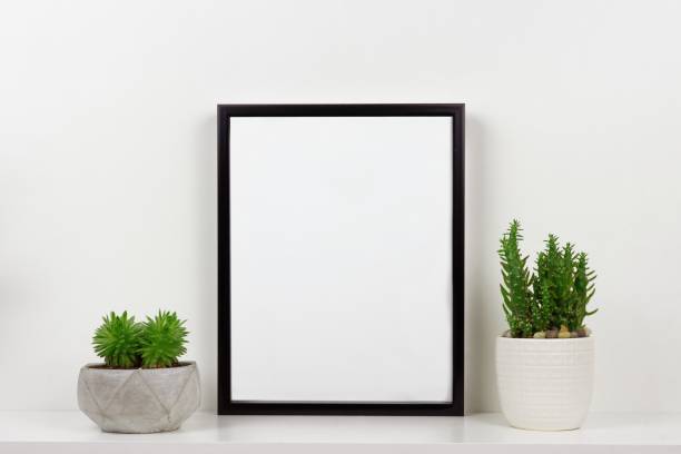 istock Mock up black portrait frame and succulent plants in pot on a white shelf 1213573631
