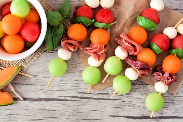 brochetas de frutas de verano con melón, queso y prosciutto, cerca de la madera - melon balls fotografías e imágenes de stock