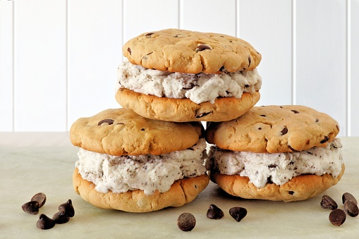 Group of chocolate chip cookie ice cream sandwiches with a white wood background
