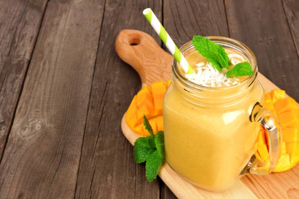 istock Mango coconut smoothie in a mason jar glass on a paddleboard against rustic wood 1213573821