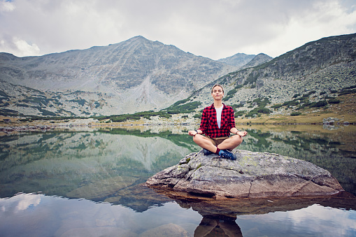 Hiker girl is practicing yoga in the mountain