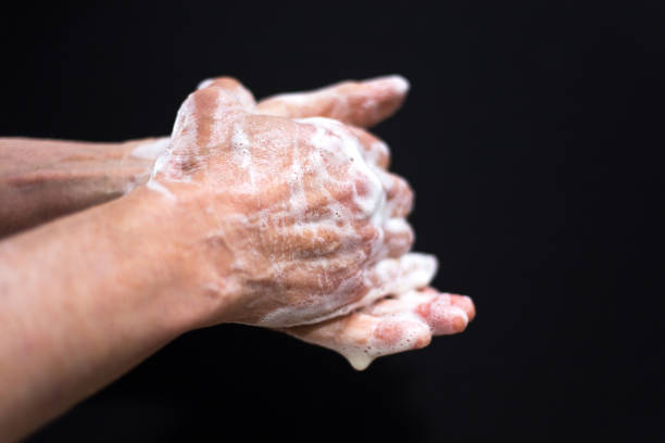 istock Man Washing Hands Close-Up Black Background Soap Suds 1213576984