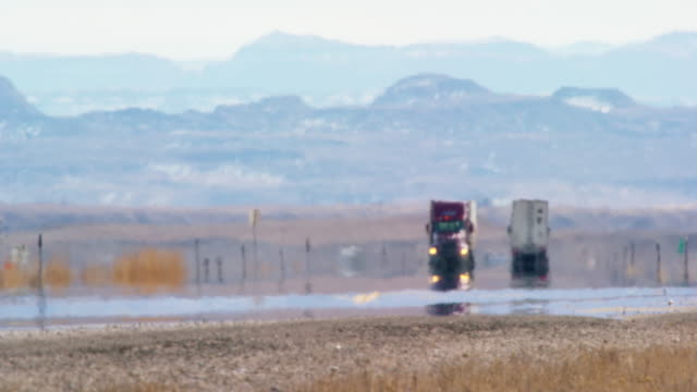 Heat Haze Distorts Video of Semi-Trucks Driving Down a Utah Interstate Surrounded by Mountains on a Sunny Day