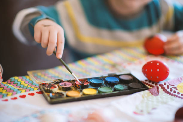istock Little boy painting Easter eggs at the table 1213579736