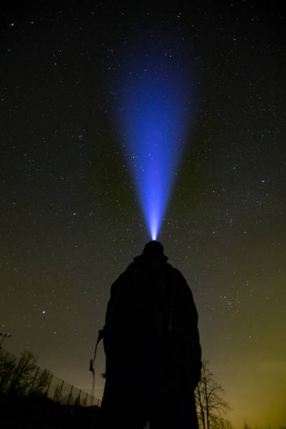istock Low Angle Rear View of Unrecognizable Adult Man Looking at Night Sky With Headlight 1213581264