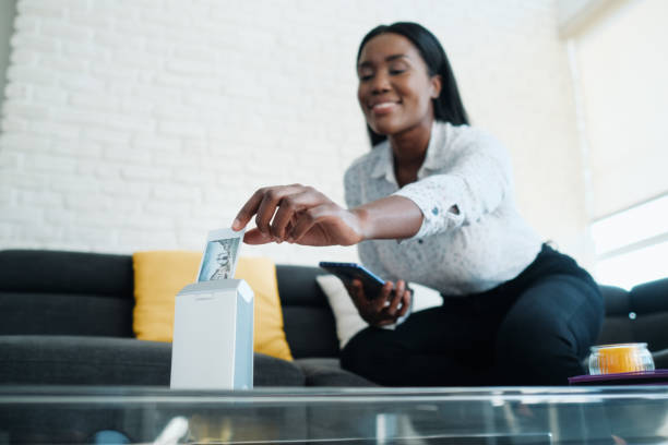 Black Woman Using Portable Wi-Fi Printer For Printing Pictures Black woman printing pictures with portable wireless mini printer at home. African american people sitting on sofa and archiving prints in photo album tiny pics pictures stock pictures, royalty-free photos & images