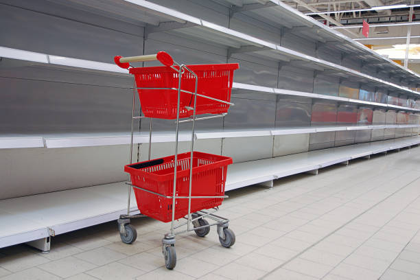 istock Shopping trolley with empty baskets by empty shelves in supermarket 1213582299