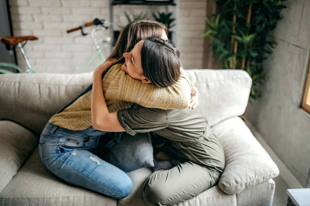 istock Sisters embracing in living room 1213582656