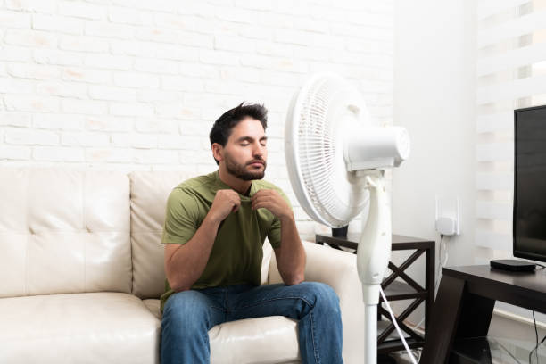 istock Hispanic Man Sitting In Front Of Fan At Home 1213582784