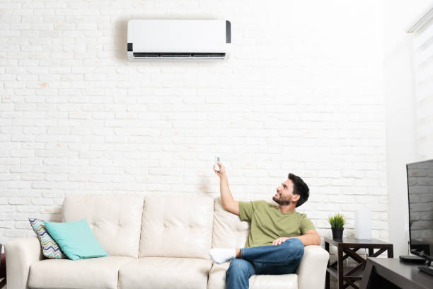 istock Latin Man Adjusting Temperature Of Mini Split At Home 1213583655