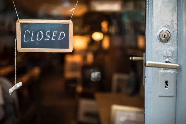 Closed - sign hanging on glass door of a shop in a city