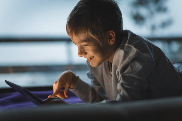 istock Cheerful boy smiling while playing video games on his digital tablet 1213589422