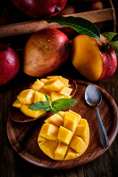 istock Tropical fruits - Low key image of mango ready to eat on table in rustic kitchen 1213590810