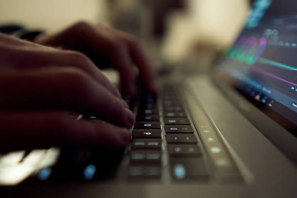 Young male freelancer content creator working on laptop during the night in low light. Young entreprenuer working late at home
