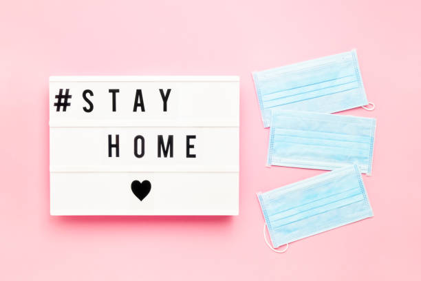 istock Three medical protective masks and STAY HOME written in light box on pink background. Healthcare and medical concept. Top view, copy space. Quarantine concept. 1213591937