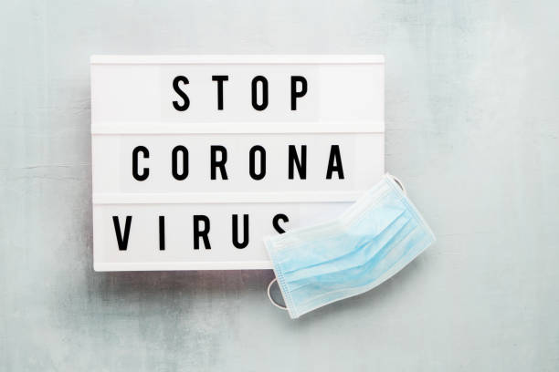 istock Medical protective mask and STOP CORONA VIRUS written in light box on blue background. Healthcare and medical concept. Top view, copy space. Quarantine concept. 1213593734