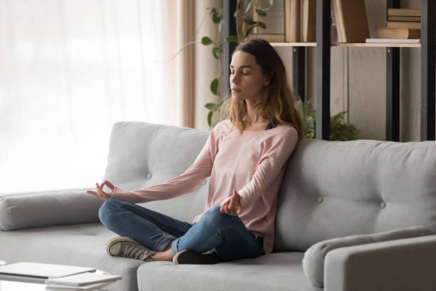 istock Healthy calm girl sit on sofa meditating doing yoga exercise 1213595721
