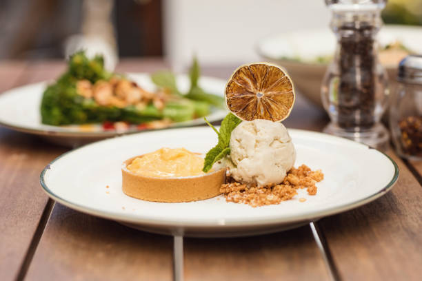 Gourmet Lemon Tart And Vanilla Bean Ice Cream Dessert Served With Mint and Citrus