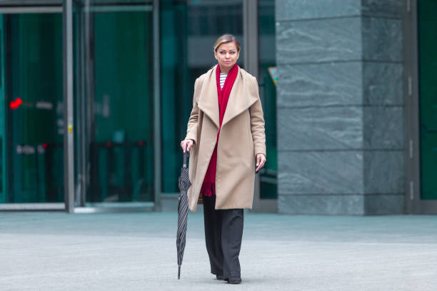 outdoors lifestyle fashion portrait of stunning brunette girl. walking on the city street. going shopping. wearing stylish white fitted coat, red neckscarf, black umbrella cane. business woman - neckscarf imagens e fotografias de stock