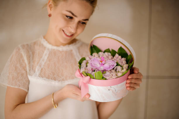 柔らかい色のピンクの小さなバラ、緑の葉と1つの蘭の春のバスケットを保持している女の子 - orchid flower single flower green ストックフォトと画像