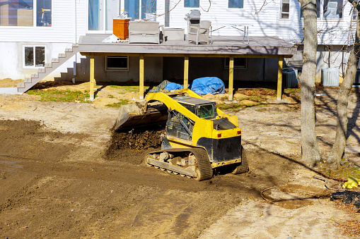 Bulldozer moving, leveling ground at construction site in ground using shovels