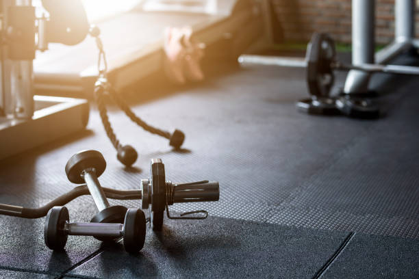 équipement de poids de forme physique de fond de gymnastique sur le plancher foncé vide - appareil de musculation photos et images de collection