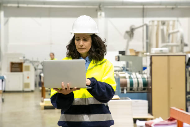 istock Focused female technician using laptop at printing house 1213617644