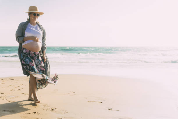 istock Smiling future mother walking on beach during vacation 1213618737