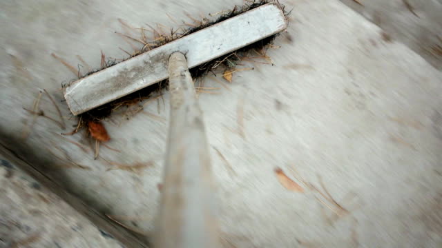 POV of an old wooden MOP that sweeps away dry leaves