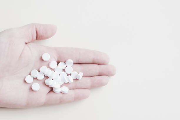 istock many white pills in the palm on a light background, medicine 1213622528