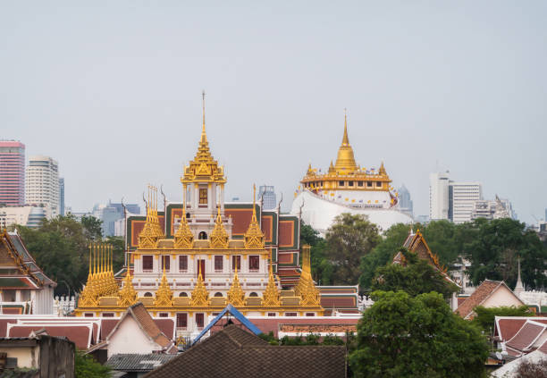 istock Loha Prasat Wat Ratchanatda and Golden Mountain pagoda, a buddhist temple or Wat Saket with skyscraper buildings in Bangkok Downtown, urban city at sunset, Thailand. Thai Landmark. Architecture. 1213627991