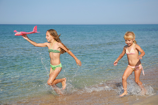 Children on the beach are posing and having fun, they jumped.