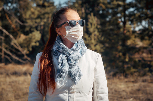 protection from diseases and coronavirus, the woman wears a medical mask and sunglasses. Spring fashion 2020.