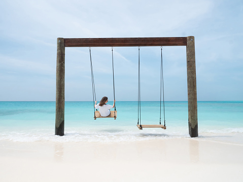 Young Woman on Swing in Indian Ocean on Tropical Maldivian Beach. Bright Summer Concept.