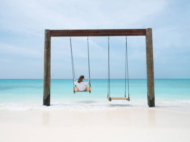 jovem mulher em swing no oceano índico na praia tropical maldiviana. conceito de verão brilhante. - arch top - fotografias e filmes do acervo