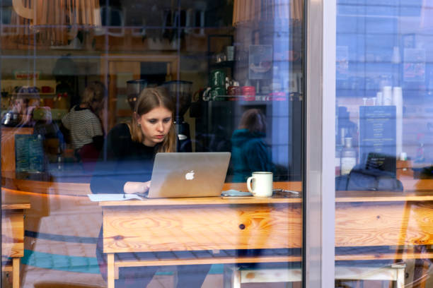 Young woman sitting in a cafe, having a cup of coffee, working on a laptop. stock photo