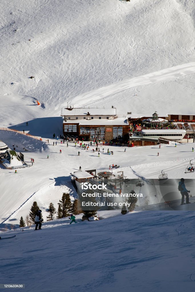 Panoramic view of the ski resort Ischgl with skiers and snowborders on the slopes. Ischgl, Austria - January 2020: Panoramic view of the ski resort Ischgl with skiers and snowborders on the slopes. Chairlifts, restaurant at the foot of the slope Station Stock Photo