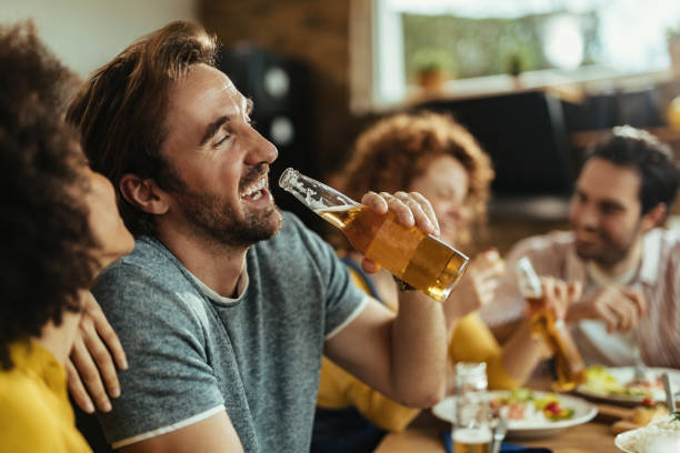 istock Cheerful man drinking beer while while having lunch with friends at home. 1213635029