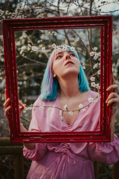 istock woman with blue hair holding red frame in spring 1213636166