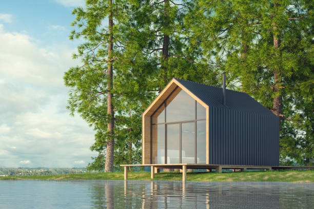 スカンジナビアのモダンなスタイルの木製の人里離れた家で、湖を見下ろす大きな窓、曲がりくねった緑の森と青空を背景に日没時の暖炉。3d イラストレーション - scandinavian lake cottage house ストックフォトと画像