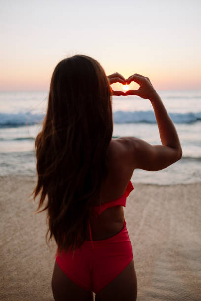 istock Woman making a heart shape with her hands on the beach 1213637991