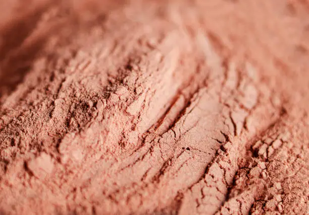 Photo of Red bentonite clay powder. Natural beauty treatment and spa background. Clay texture close up, selective focus.