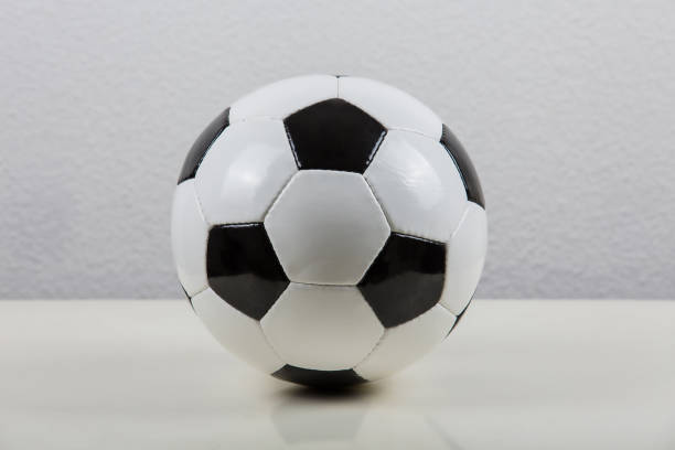 istock Classic football ball on the table, black and white typical hexagon pattern, isolated on  grey background. Real, traditional soccer ball symbol. 1213640876
