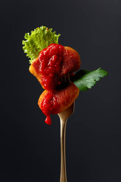 istock Fried chicken nuggets with ketchup, parsley and salad on a fork. 1213640930