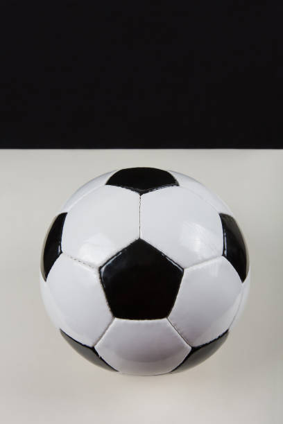 istock Classic football ball, typical hexagon pattern, isolated on grey table with black copy space background above. Real, traditional soccer ball symbol, vertical photo. 1213641032