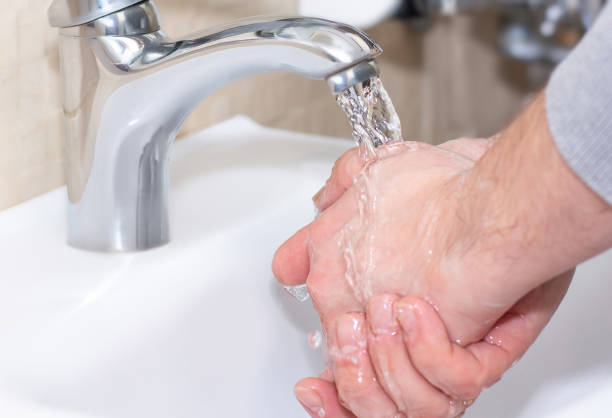 a man washes his hands under running water. close-up photo. health, cleanliness and hygiene concept. - water human hand stream clean imagens e fotografias de stock