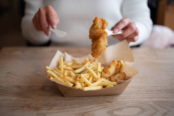 Young asian woman eating a fish & chips meal in fast-food restaurant