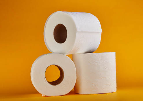 White toilet paper rolls on vivid yellow / orange background