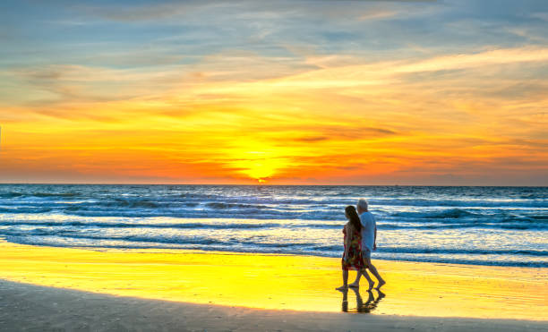 A silhouette of a foreign tourist couple happily walking together along a white sand beach Mui Ne, Vietnam - March 4th, 2020: A silhouette of a foreign tourist couple happily walking together along a white sand beach when the sunrise is peaceful in Mui Ne, Vietnam mui ne bay photos stock pictures, royalty-free photos & images